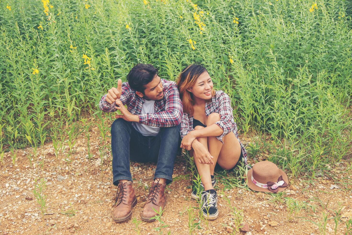 jonge gelukkige hipster paar zitten in het gele veld, dating genieten van tijd samen. foto