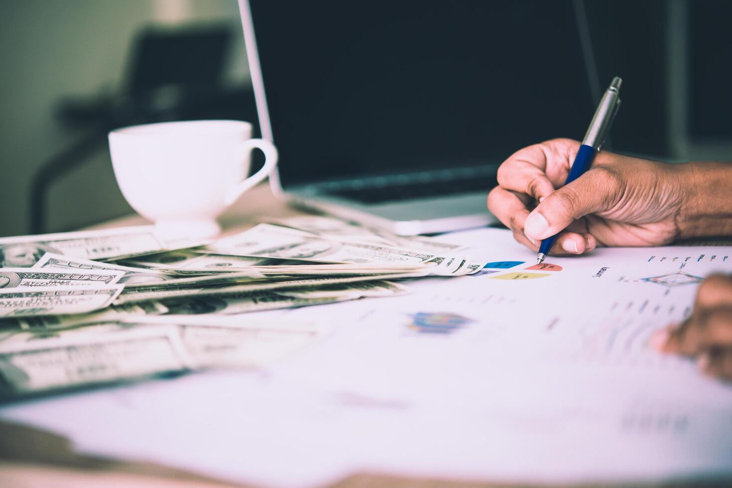 werkplaats van de handelaar. de tafel gedekt door bankbiljetten, toetsenbord en financiële grafieken. zakelijk financieel werken. foto