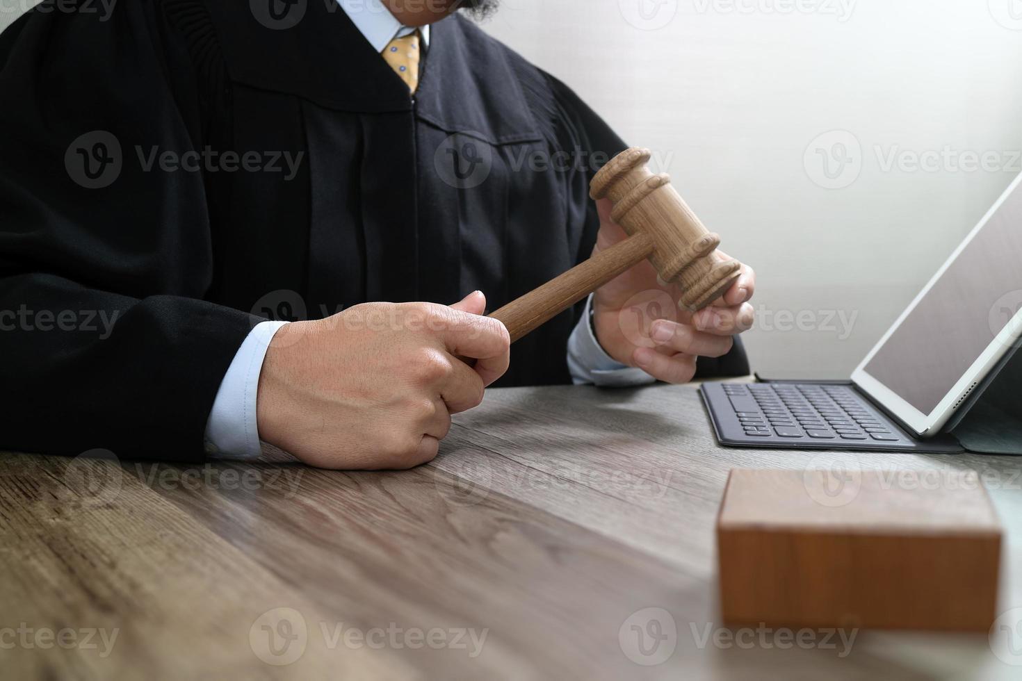 rechtvaardigheid en recht concept.male rechter in een rechtszaal met de hamer, werken met digitale tabletcomputer docking toetsenbord op houten tafel foto