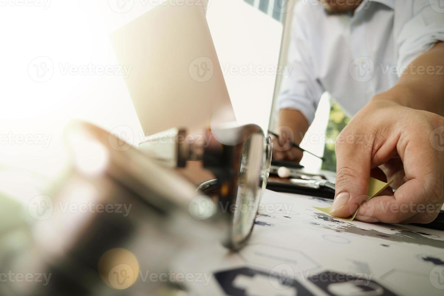 arts die met laptopcomputer in medisch werkruimtebureau en medisch netwerkmediadiagram werkt met stethoscoop en lenzenvloeistofvoorgrond als concept foto