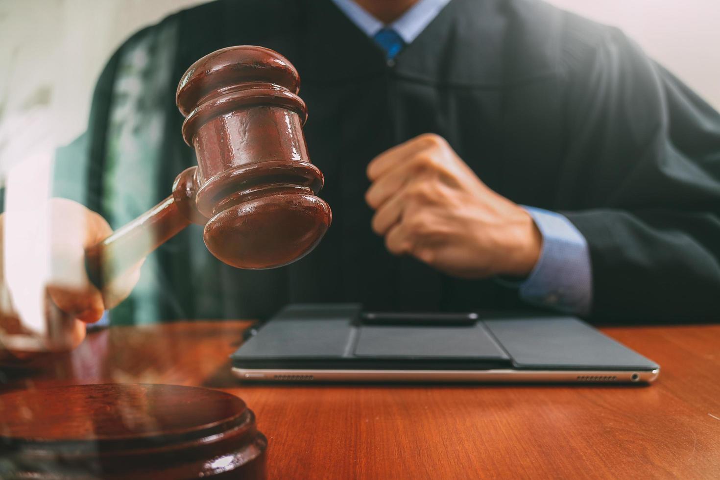 rechtvaardigheid en recht concept.male rechter in een rechtszaal die de hamer slaat, werkend met digitale tabletcomputer docking toetsenbord op houten tafel, filtereffect foto