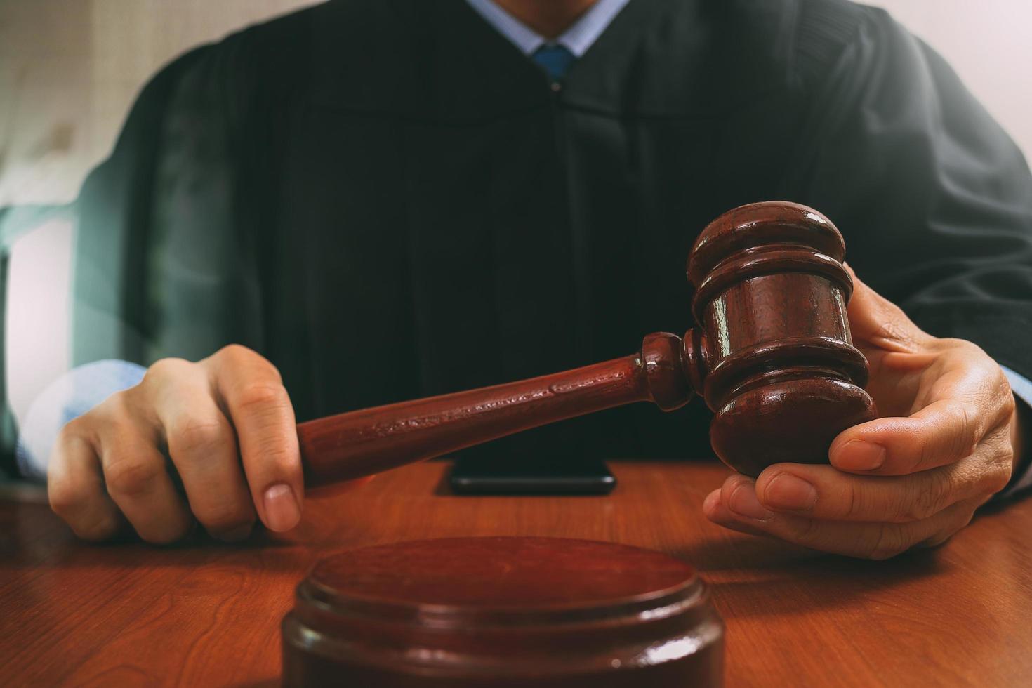 rechtvaardigheid en recht concept.male rechter in een rechtszaal die de hamer slaat, werkend met digitale tabletcomputer docking toetsenbord op houten tafel, filtereffect foto