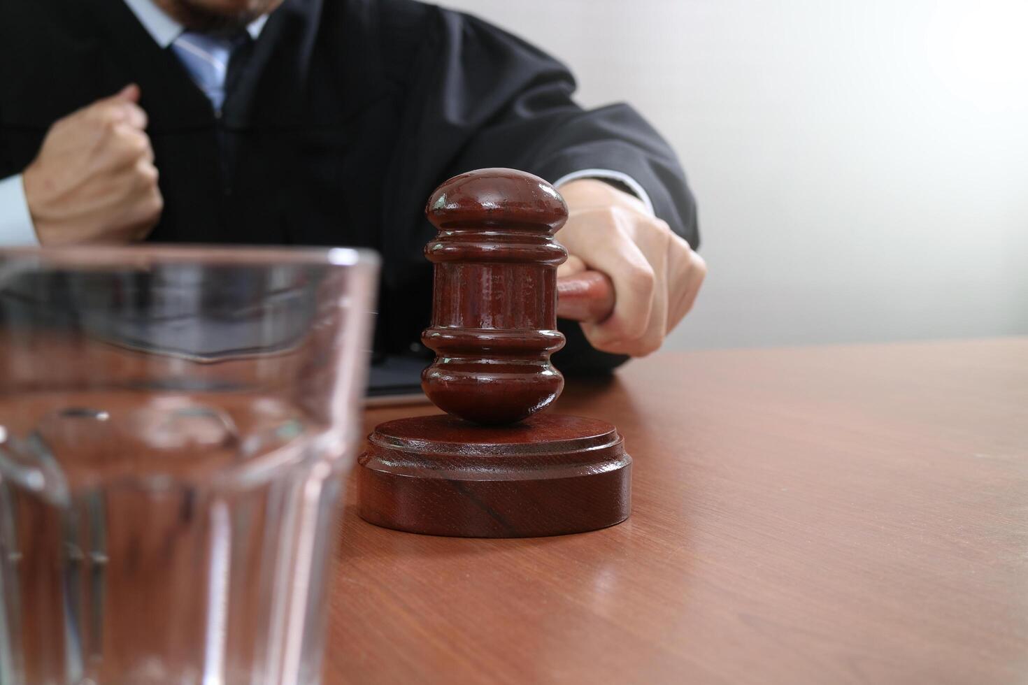 rechtvaardigheid en recht concept.male rechter in een rechtszaal met de hamer, werken met slimme telefoon, digitale tabletcomputer docking toetsenbord op houten tafel foto