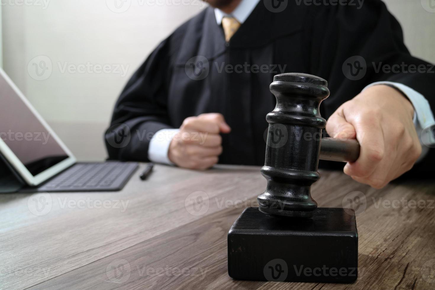 rechtvaardigheid en recht concept.male rechter in een rechtszaal die de hamer slaat, werkend met digitale tabletcomputer docking toetsenbord op houten tafel foto