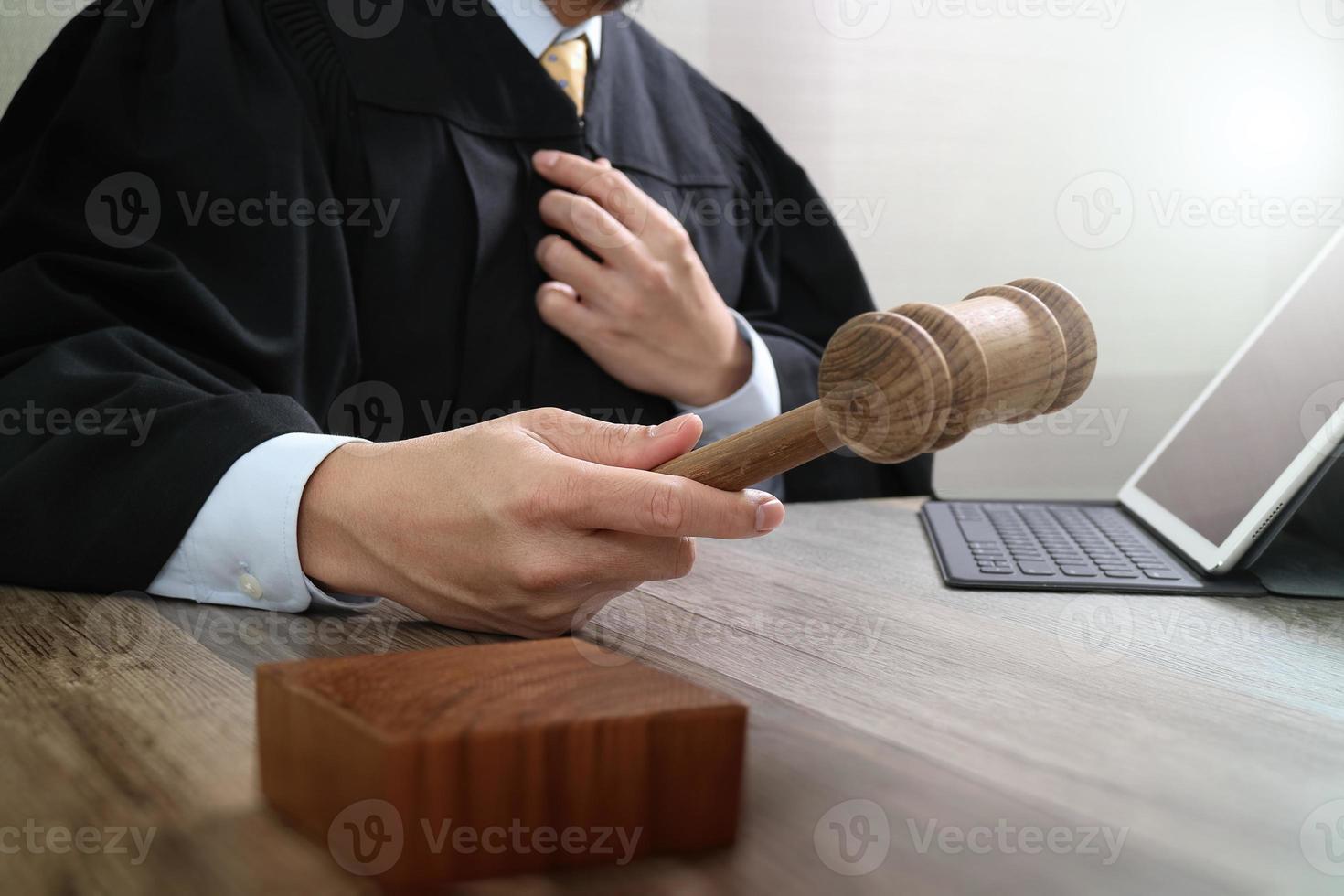 rechtvaardigheid en recht concept.male rechter in een rechtszaal met de hamer, werken met digitale tabletcomputer docking toetsenbord op houten tafel foto