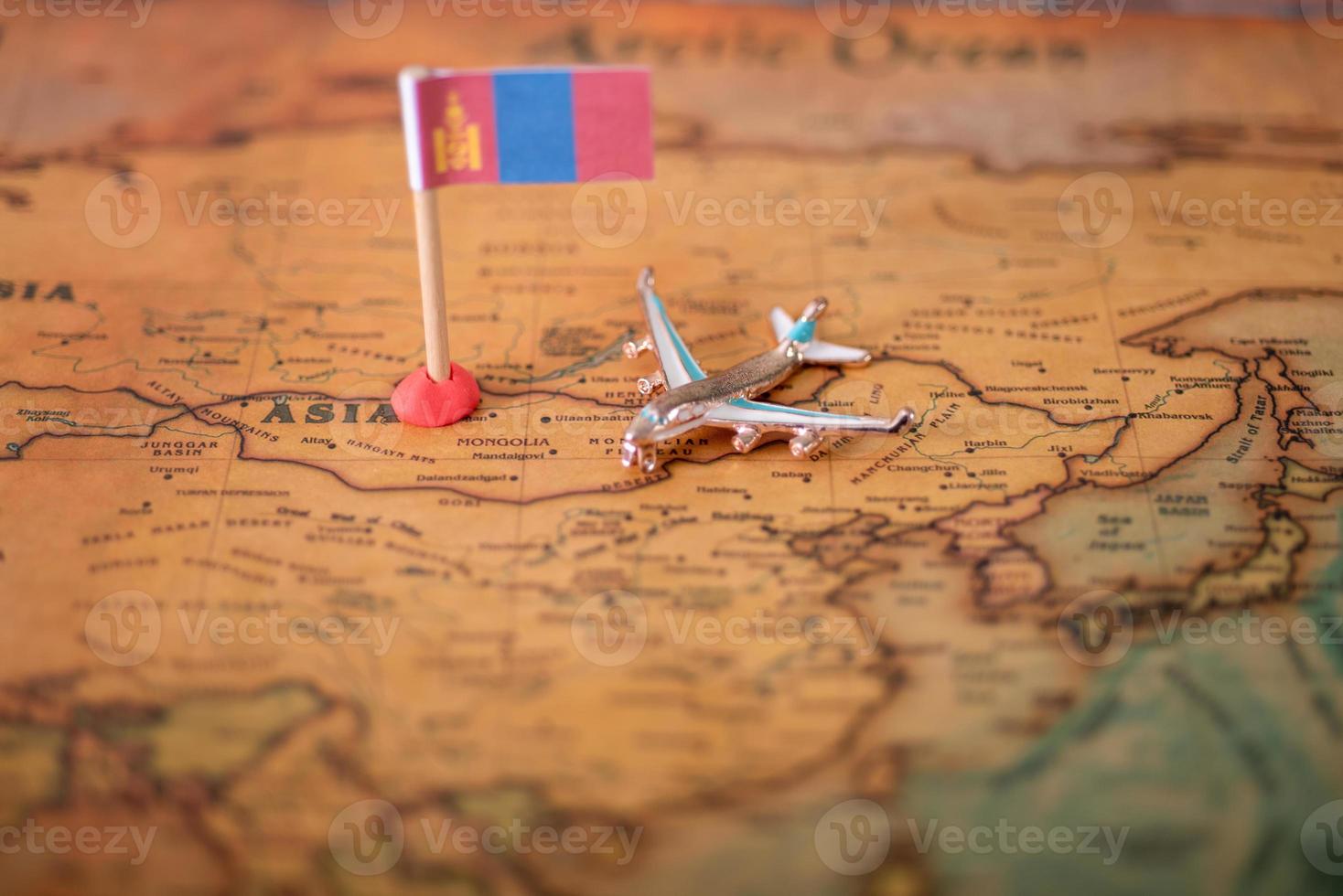 de vlag van mongolië en het vliegtuig op de wereldkaart. foto