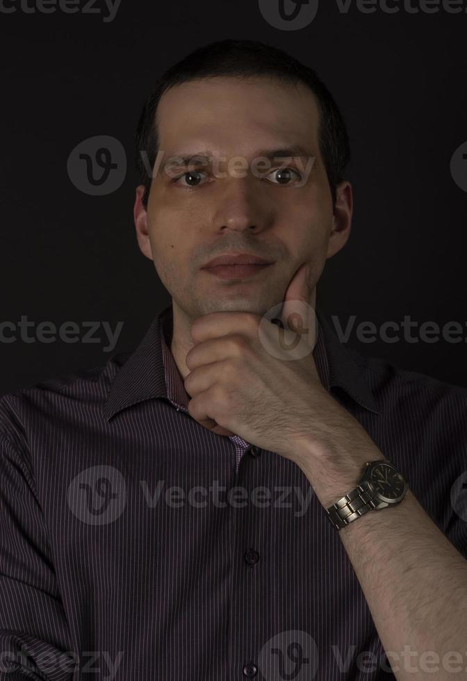 een man in een karmozijnrood shirt op een zwarte achtergrond. foto