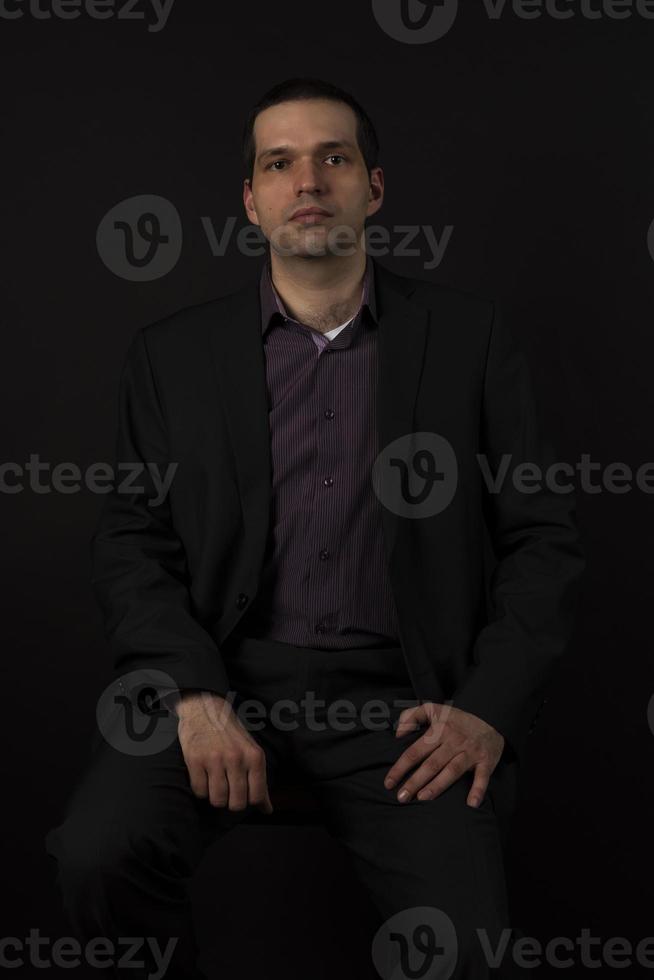 een man in een zwart pak op een zwarte achtergrond. foto