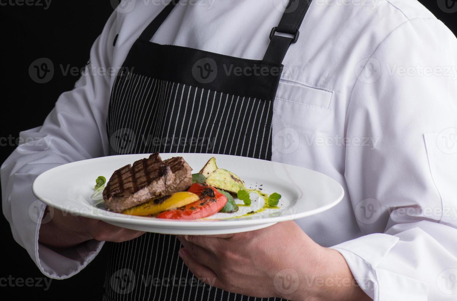 chef-kok in uniform serveert een gerecht op een bord foto