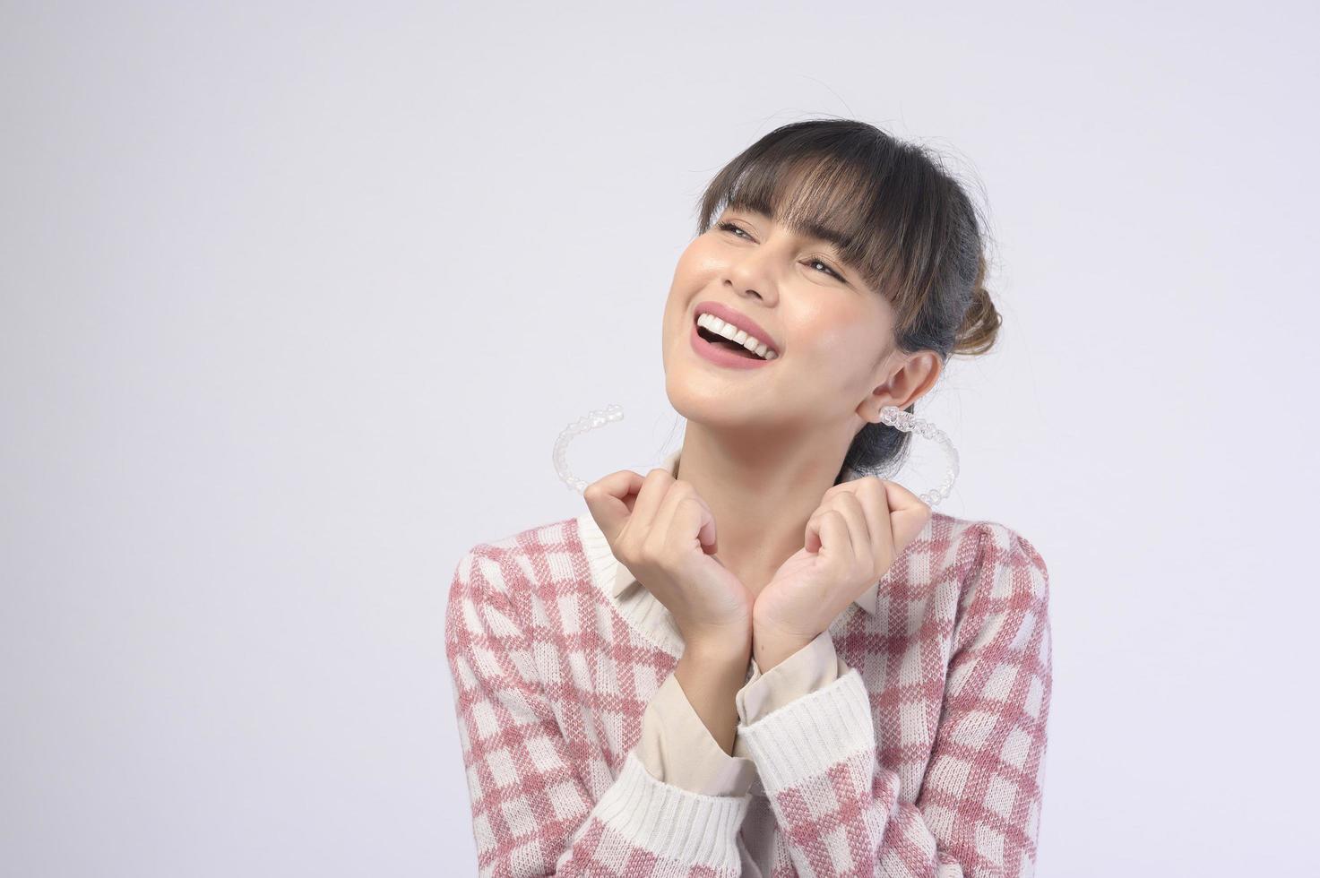 jonge lachende vrouw met invisalign beugels op witte achtergrond studio, tandheelkundige zorg en orthodontische concept. foto