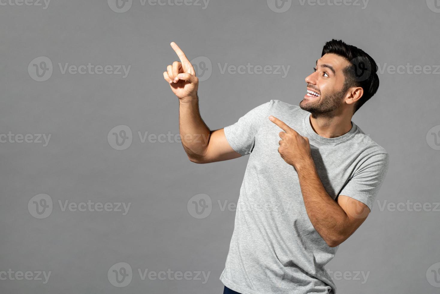 portret van een verraste jonge blanke man met handen die omhoog wijzen in een geïsoleerde lichtgrijze studioachtergrond foto