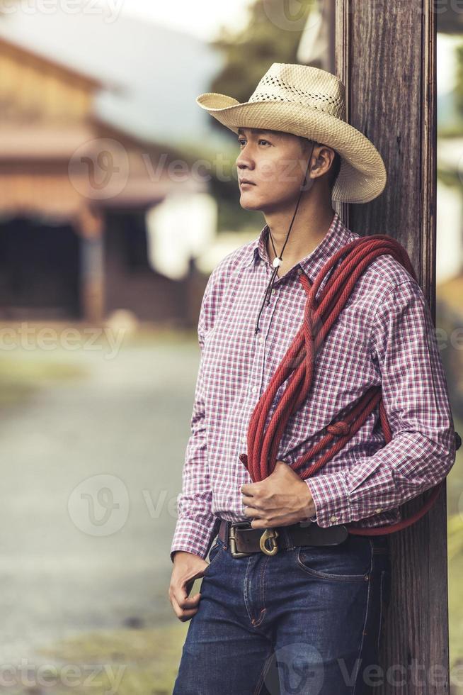 knappe jonge man met cowboyhoed die staat te denken foto