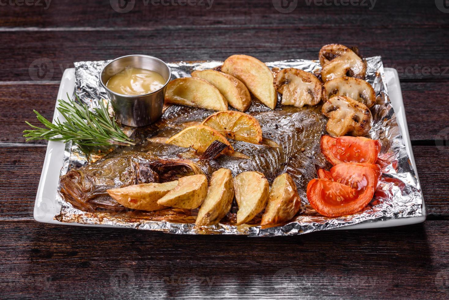 smakelijke gebakken vis met aardappelen en tomaten op een witte rechthoekige schotel foto