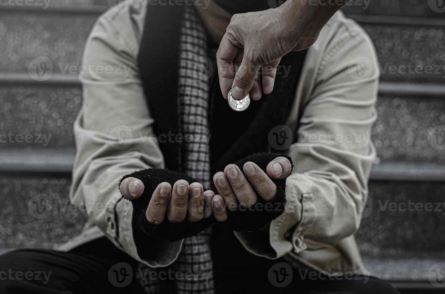 close-up van de armen of daklozen daklozen vragen in het openbaar om geld. de arme bedelaar in de stad zat op de trap met een zilveren mok. foto