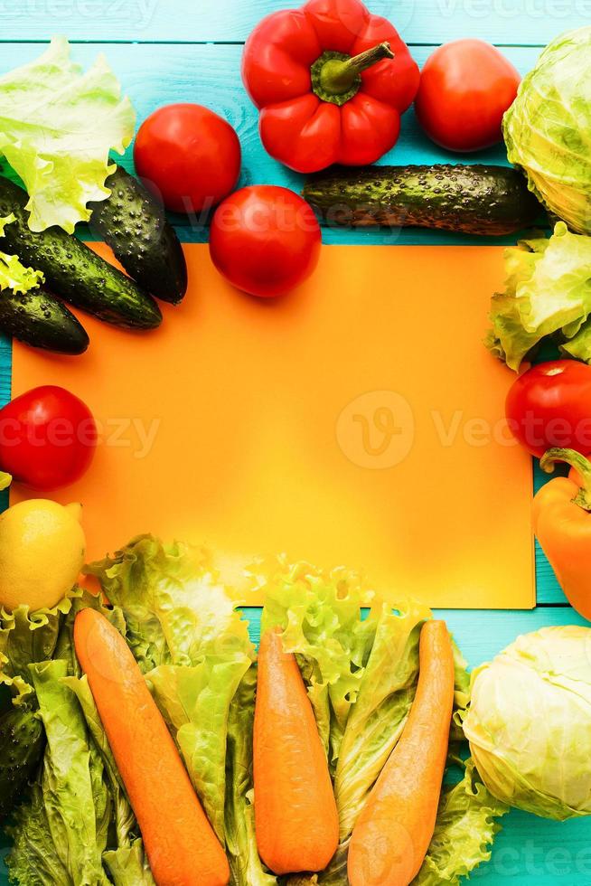 frame van groenten met receptpapier op blauwe houten ondergrond. bovenaanzicht foto