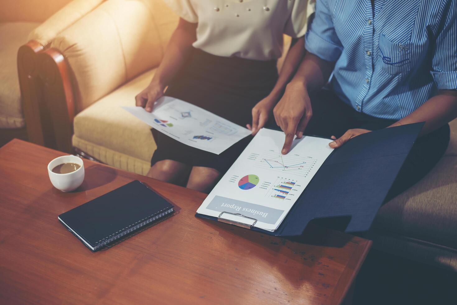 secretaresse die haar handen wijst om financiële grafiek aan haar partner uit te leggen. foto