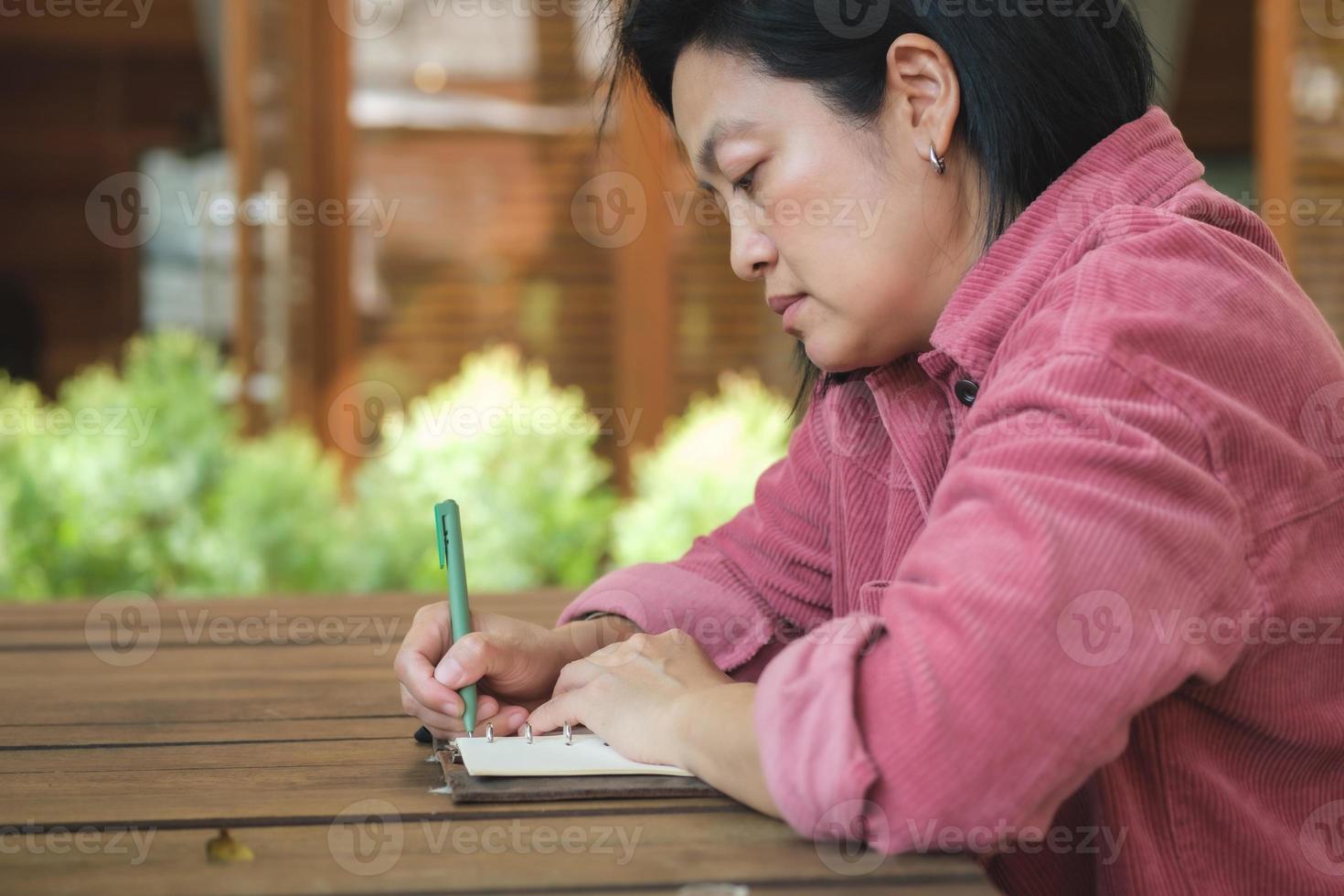 vrouw schrijft doel op notitieboekje bij coffeeshop buitenruimte foto
