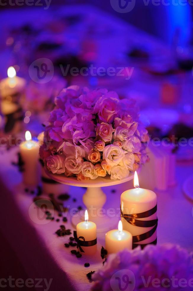 mooie, gedecoreerde tafel met bloemdecoraties en rode kaarsen. kerstavond of bruiloft feestdecoratie. foto