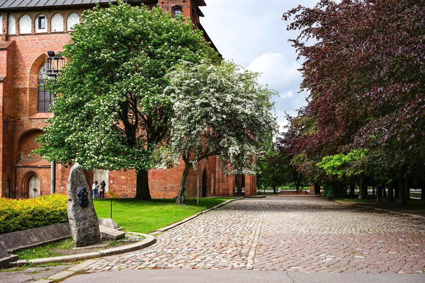 Kaliningrad, Rusland-18 mei 2016-een mijlpaal van de kathedraal van de oude stad onder de bewolkte hemel tussen de groene bomen. foto