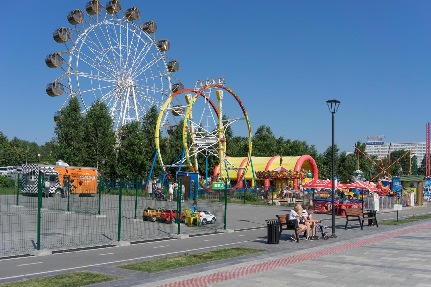 Novosibirsk, Rusland-16 juli 2018 -stadslandschap met uitzicht op het pretpark en de promenade van de stad met vakantiegangers. foto