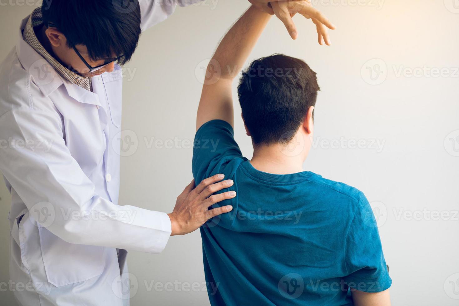 chiropractor die de arm van een jonge man in een medisch kantoor uitrekt foto