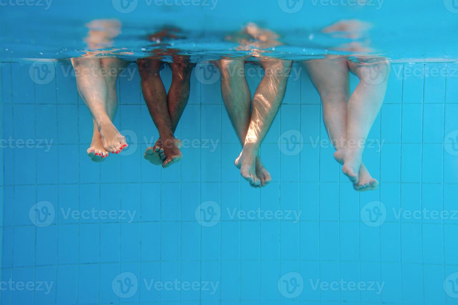 benen van Afro-Amerikaanse man met blanke vrienden in zwembad onder water. zomer. vakantie, internationaal en sportconcept. foto