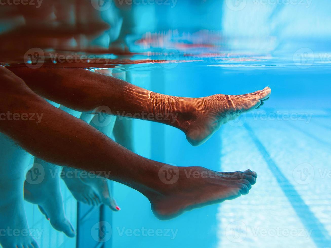 benen van Afro-Amerikaanse man met blanke vrienden in zwembad onder water. zomer. vakantie, internationaal en sportconcept. foto