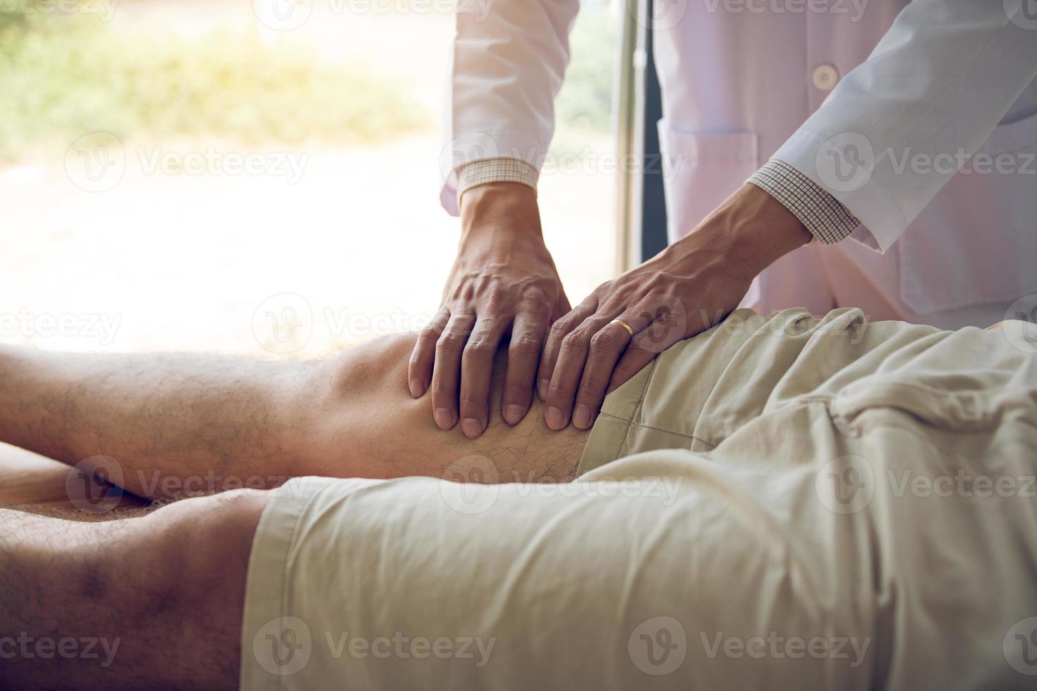 fysiotherapeuten gebruiken de handen om de dij van de patiënt vast te pakken om te controleren op pijn en massage in de kliniek. foto