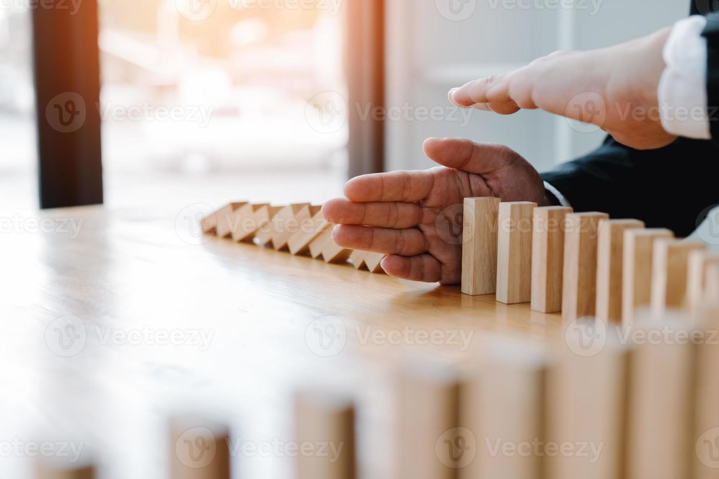 risicoconcept met hand van zakenman die het domino-effect stopt en beschermt. foto