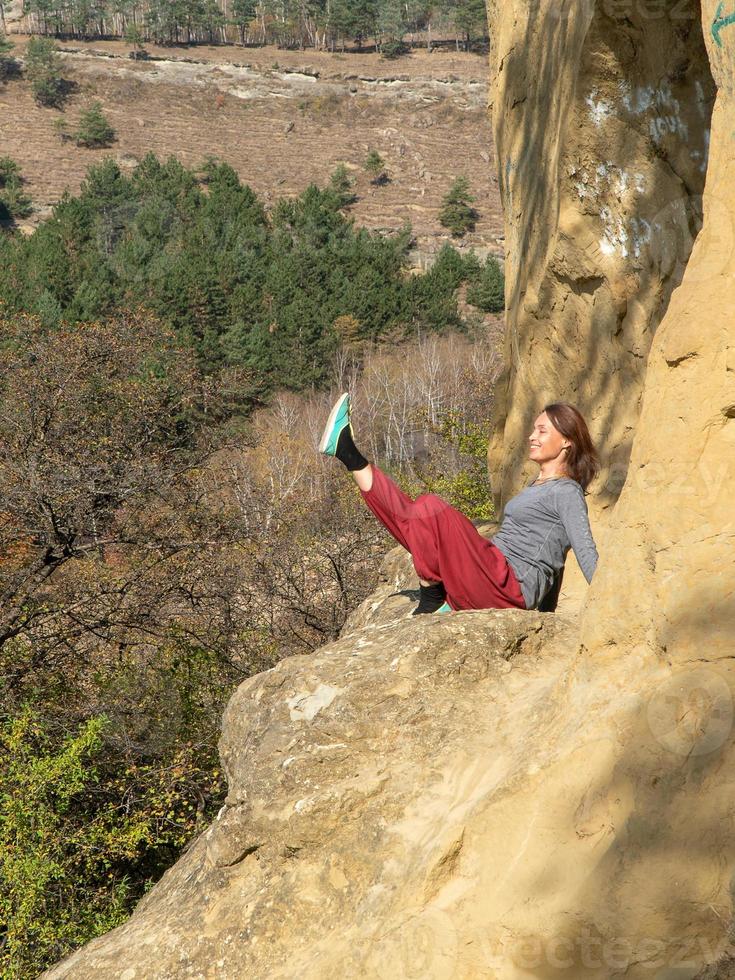 lachende vrouw met gesloten ogen zittend op een berg en yoga navasana beoefenend op een herfstdag foto