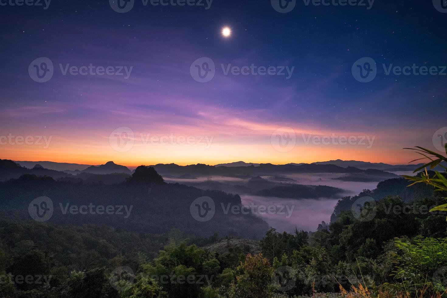 gezichtspunt zonlicht over berg met de maan bij dageraad foto