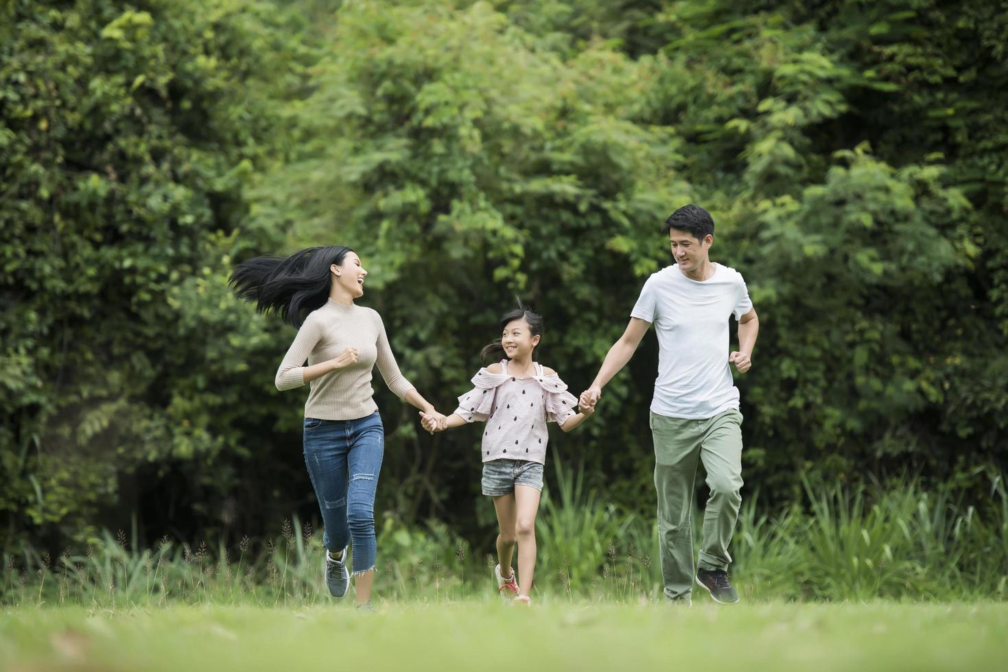 gelukkige familie heeft plezier moeder, vader en dochter rennen in het park. foto