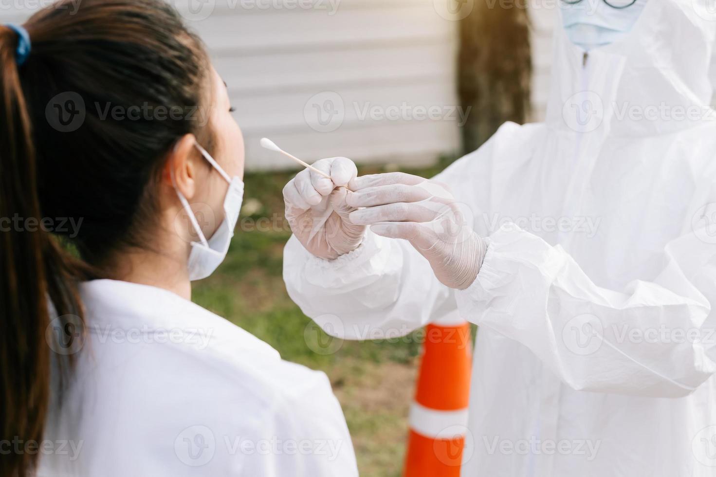 arts die covid-19- of coronavirustest of dna-test doet bij een jonge vrouw met een neusuitstrijkje, foto