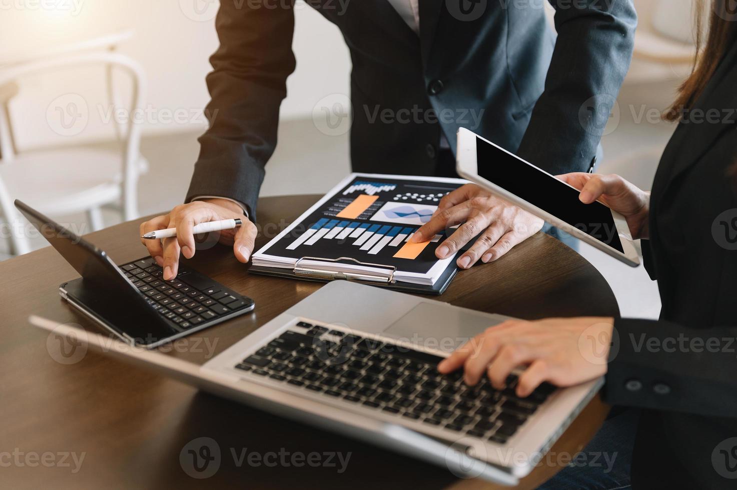 zakelijke documenten op kantoortafel met slimme telefoon en rekenmachine digitale tablet en grafiek zaken met sociaal netwerkdiagram en twee collega's die gegevens bespreken foto