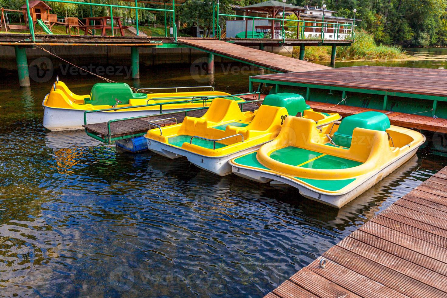 waterfietsen of waterfietsen catamarans station. gele waterfietsen vergrendeld op de pier van de jachthaven van het meer op zonnige zomerdag. zomer vrijetijdsbesteding buitenshuis. foto