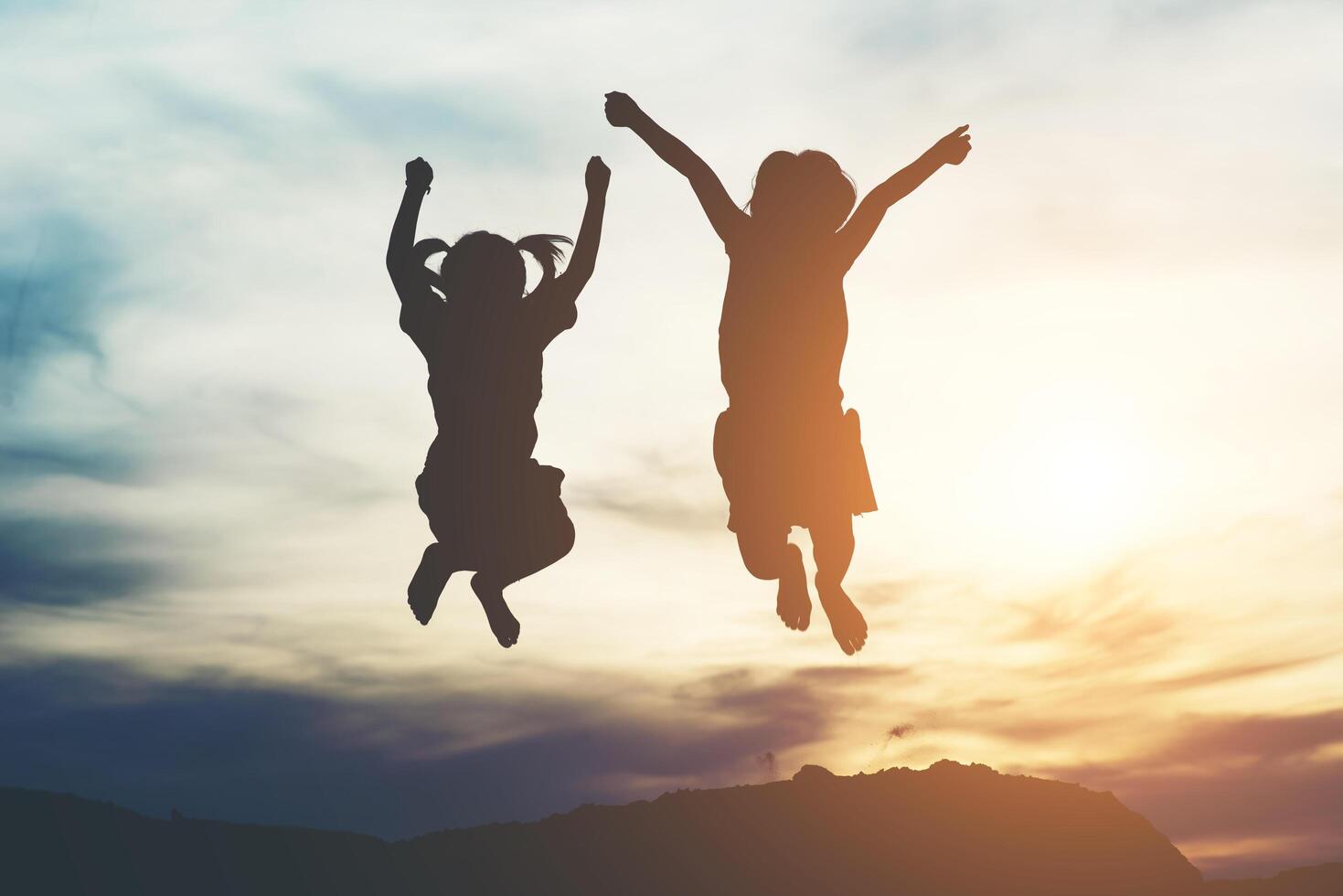 silhouet van twee meisjes die plezier hebben in de natuur foto