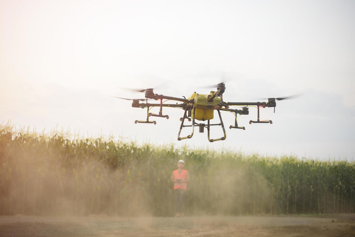 mannelijke ingenieur die drones bestuurt die kunstmest en pesticiden over landbouwgrond sproeien, geavanceerde technologische innovaties en slimme landbouw foto