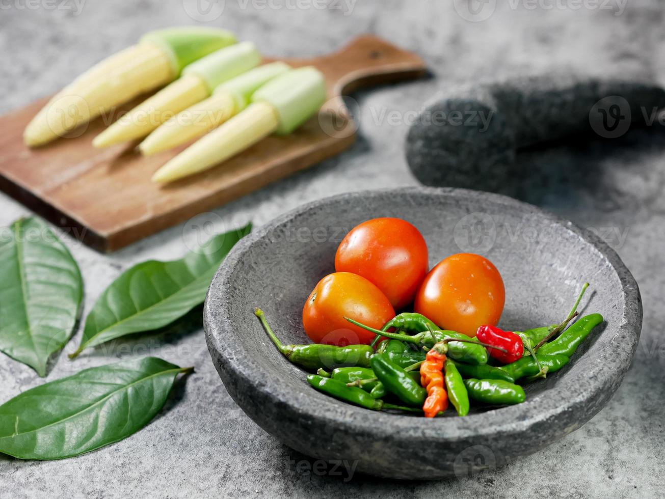 cayennepeper en tomaten in een stenen vijzel. recept tomatensaus. voedsel koken concept foto