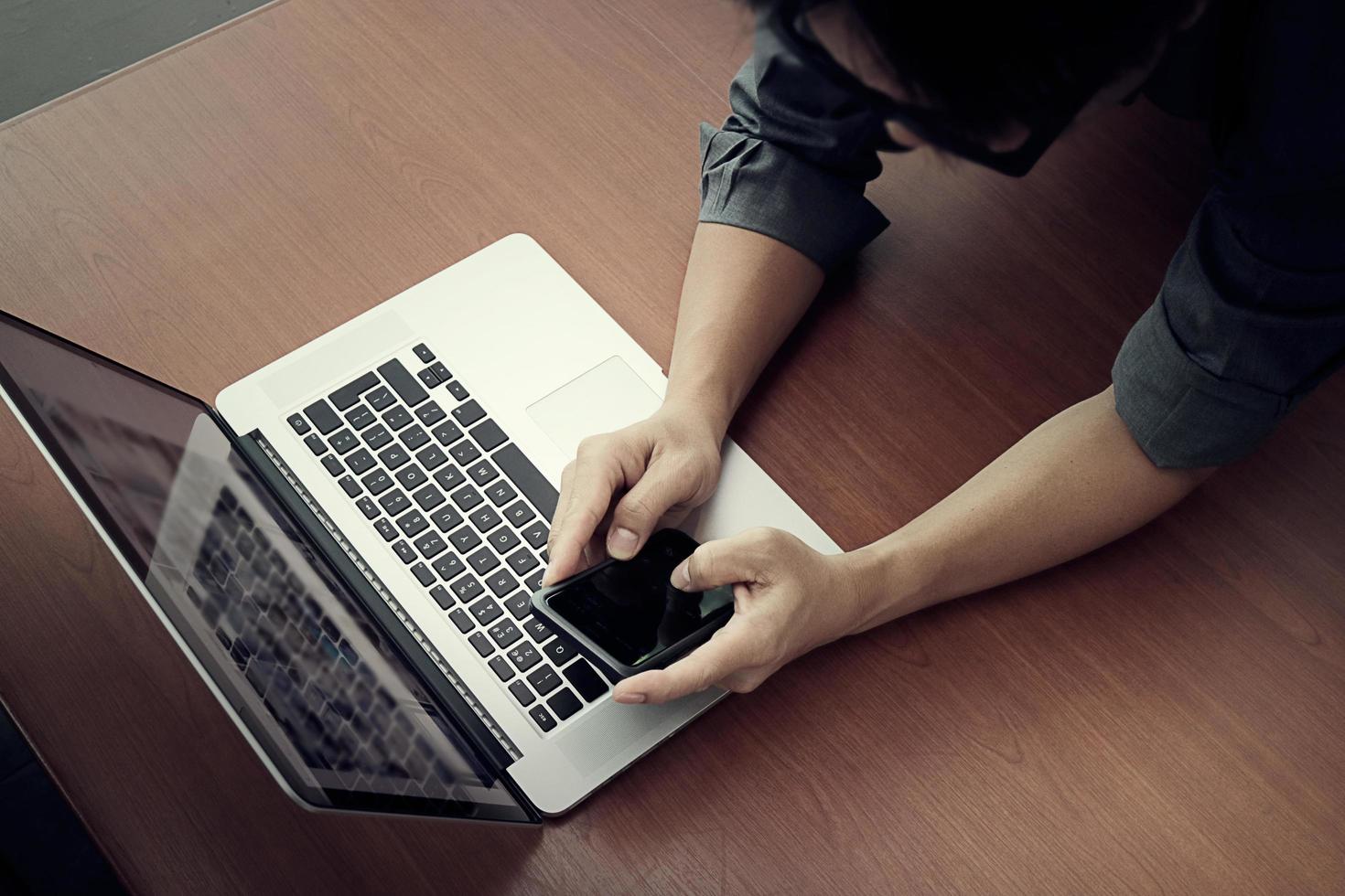 bovenaanzicht van zakenman hand werken met nieuwe moderne computer en slimme telefoon en bedrijfsstrategie op houten bureau als concept foto