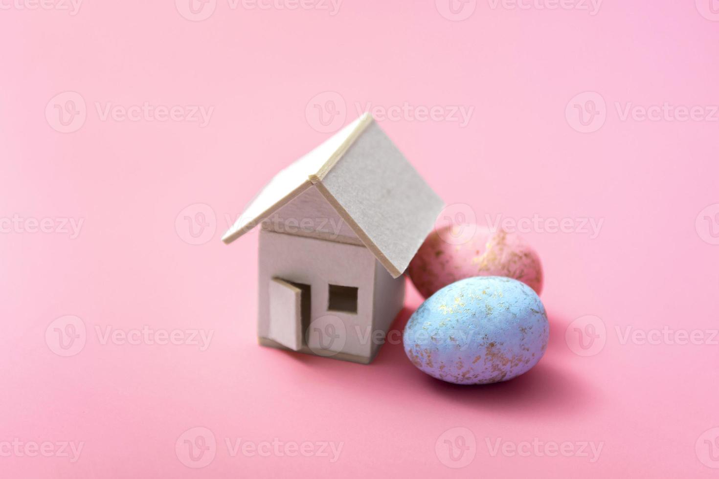 paaseieren en huis op een roze achtergrond. familie vakantie concept. wenskaartsjabloon. ruimte kopiëren. detailopname foto