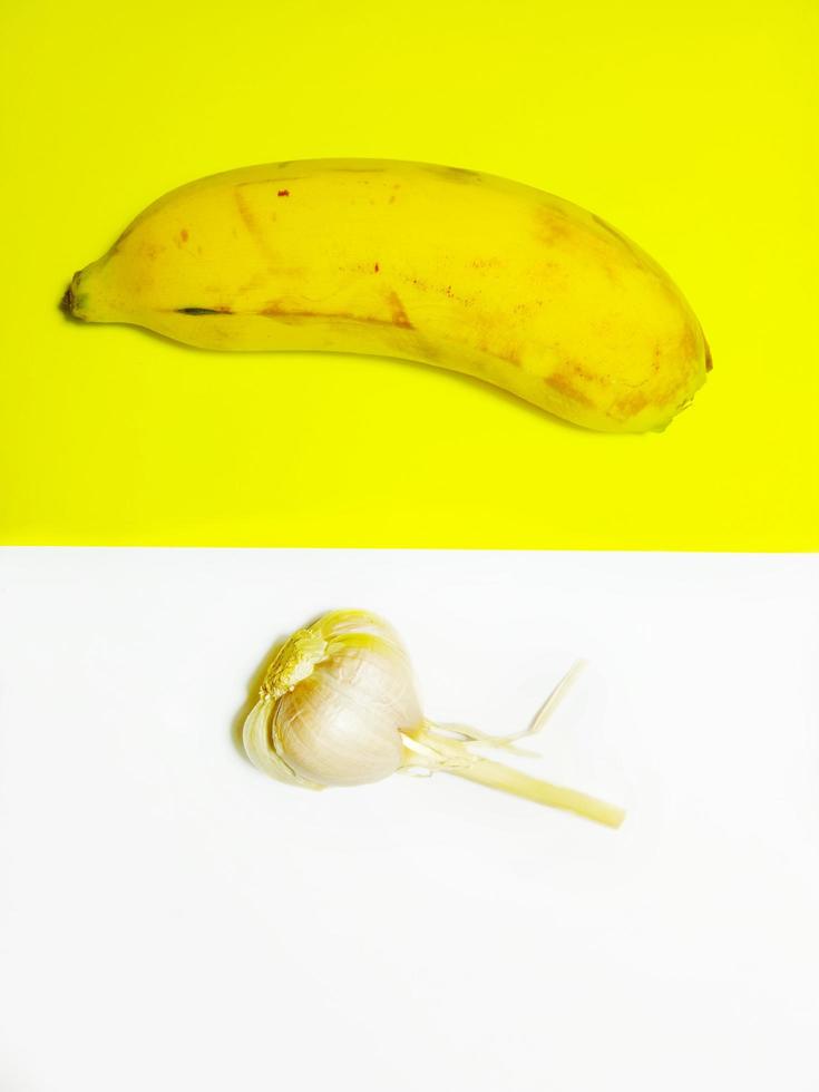 minimalistische foto van banaan en knoflook op een gele en witte achtergrond.