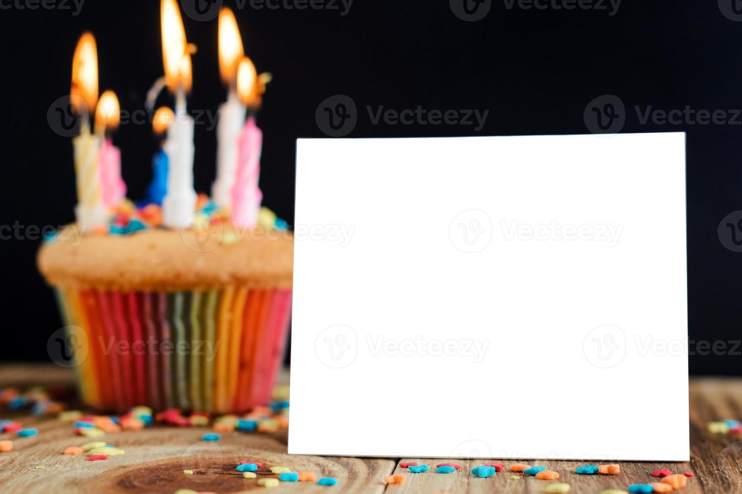 cupcake met brandende kaarsen op een houten achtergrond foto