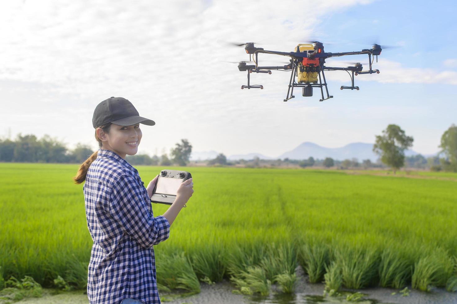 jonge slimme boer die drones bestuurt die kunstmest en pesticiden over landbouwgrond sproeien, geavanceerde technologische innovaties en slimme landbouw foto