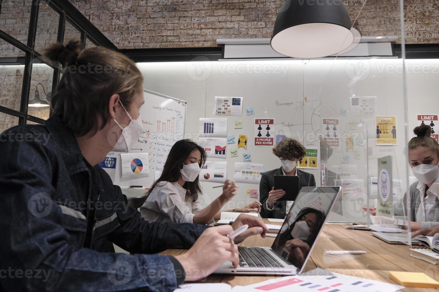 multiraciale collega's team business brainstormde werken, bespreken met blanke baas in een nieuw normaal kantoor, covid-19 bescherming door vrijgemaakte partitie werkplek, sociale afstand en gezichtsmasker. foto