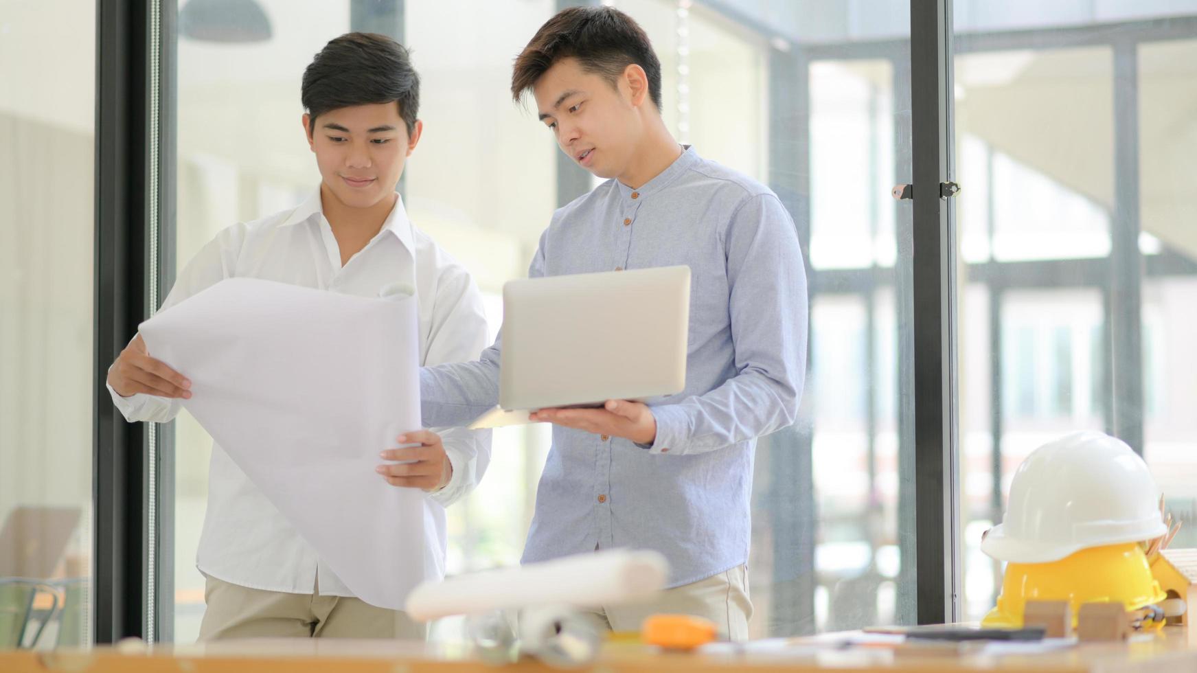 architecten en ingenieurs inspecteren plattegronden en gebruiken laptops om bouwwerkzaamheden te ontwerpen en te plannen. foto