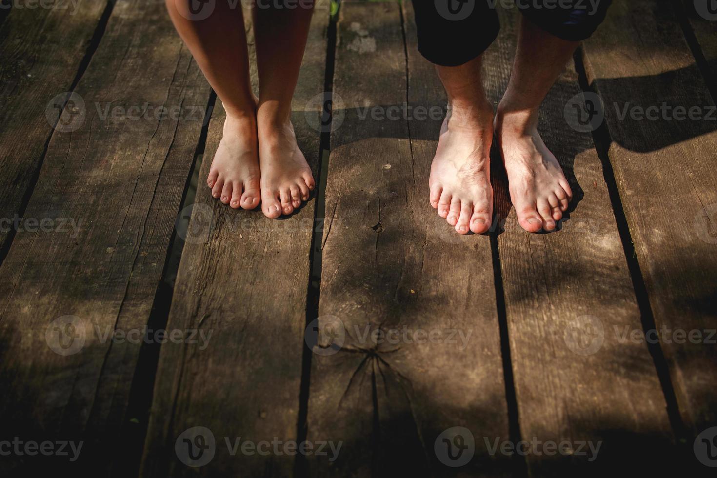 bovenaanzicht blote voeten van mannelijk en vrouwelijk paar staande op houten brug foto