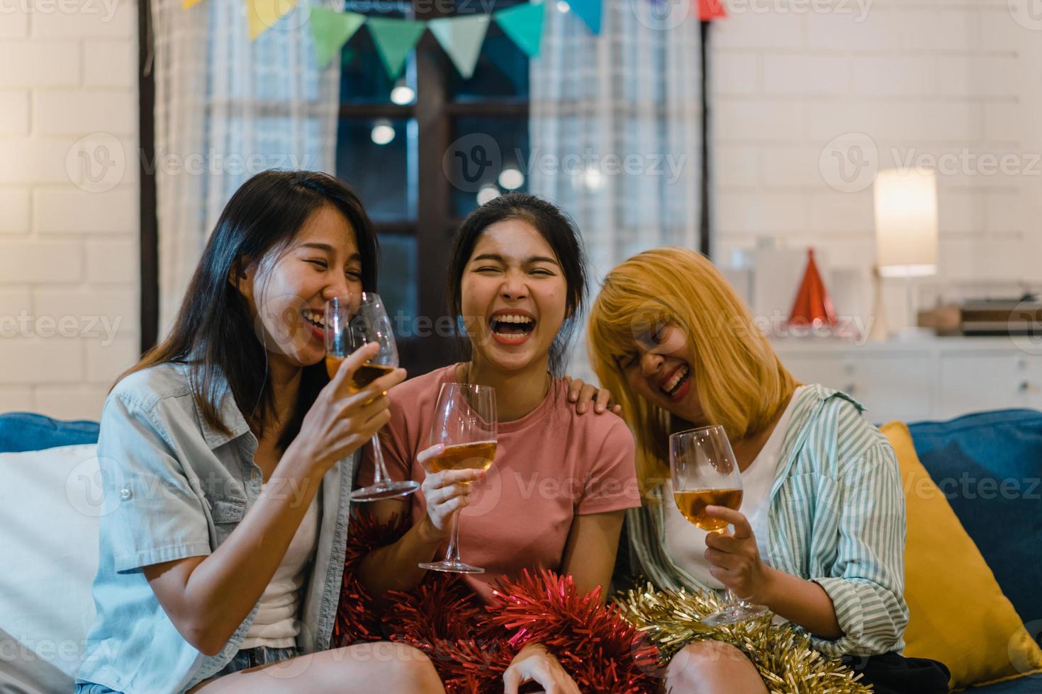 groep aziatische vrouwen feest thuis, vrouwelijke cocktail drinken praten met grappig samen op de bank in de woonkamer in de nacht. tiener jonge vriend speelspel, vriendschap, vier vakantieconcept. foto