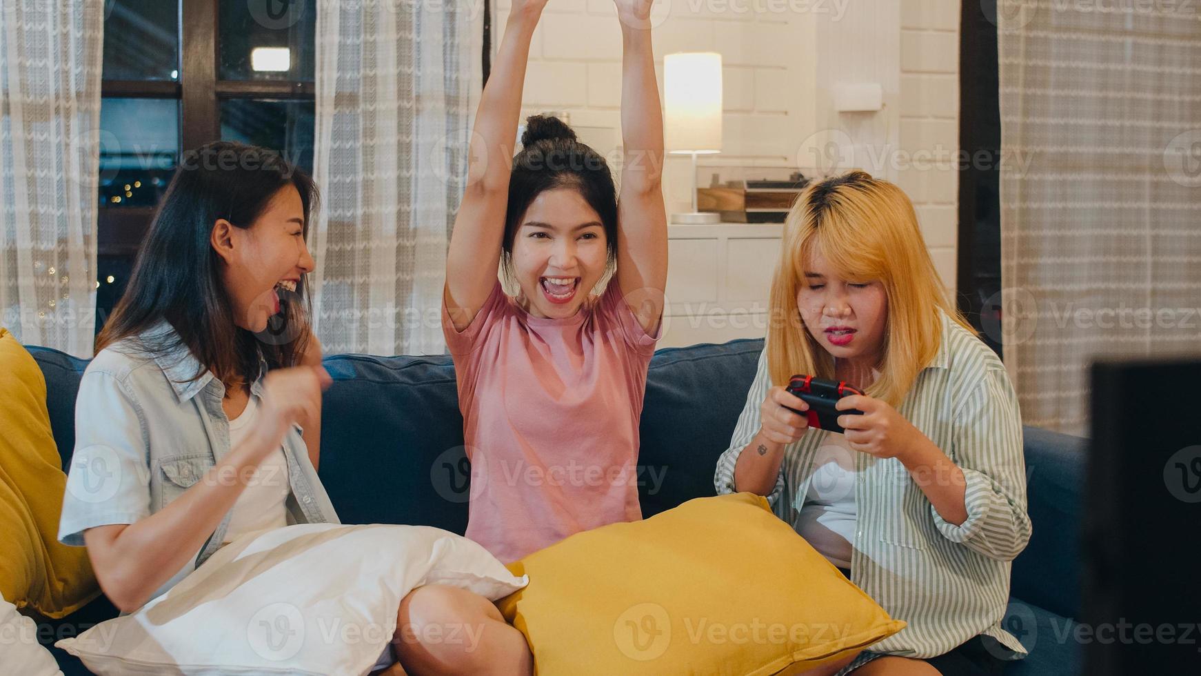 groep aziatische vrouwen koppelt spelletjes thuis, vrouwen met joystick hebben een grappig moment samen op de bank in de woonkamer in de nacht. tiener jonge vriend voetbalfan, vieren vakantieconcept. foto