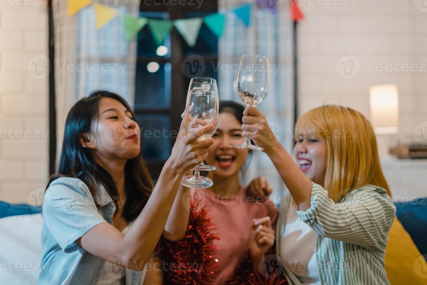 groep aziatische vrouwen feest thuis, vrouwelijke cocktail drinken praten met grappig samen op de bank in de woonkamer in de nacht. tiener jonge vriend speelspel, vriendschap, vier vakantieconcept. foto