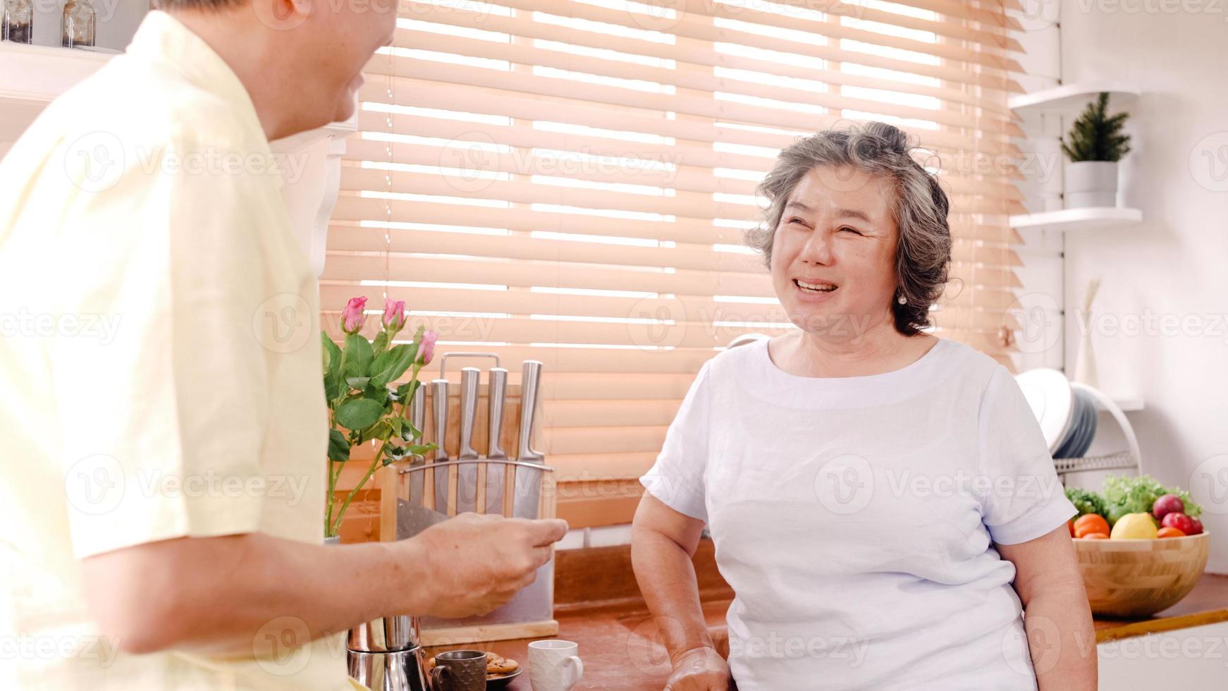 Aziatische bejaarde echtpaar ontbijten in de keuken thuis. chinees lief stel man die koekjes thuis aan zijn vrouw voedt. levensstijl senior gezin thuis concept. foto